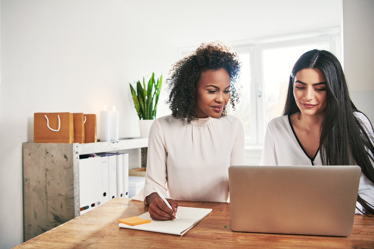 two business women working together looking at a laptop